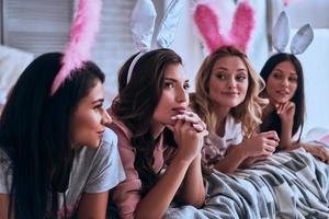 conejitos locos cuatro atractivas mujeres jóvenes con orejas de conejo sonriendo mientras están acostadas en la cama