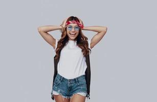 Attractive stylish young woman looking at camera and smiling while standing against grey background photo