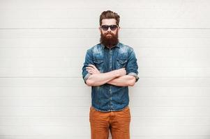 Bearded and stylish. Confident young bearded man looking at camera and keeping arms crossed while standing outdoors photo