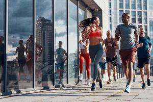 toda la longitud de la gente con ropa deportiva trotando mientras hace ejercicio en la acera al aire libre foto