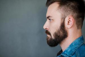 Serious and confident. Side view of young man looking away while standing against white background photo