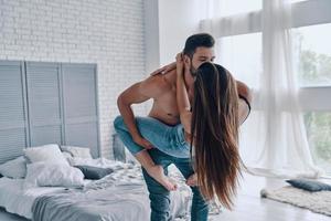 siempre felices juntos. hermosa joven pareja abrazándose mientras está de pie cara a cara en el dormitorio foto