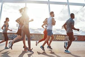 toda la longitud de los jóvenes en ropa deportiva trotando al aire libre foto