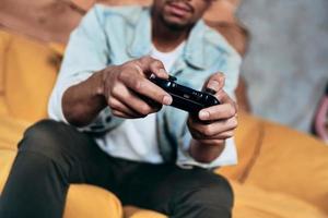 Spending carefree time. Close up of young man in casual clothing playing video games while spending time at home photo