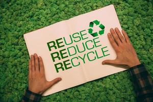 Live green. Top view close-up image of man holding hands on his notebook with text and recycle symbol at moss background photo