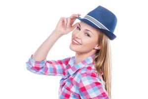 Funky style. Beautiful young woman in funky wear adjusting her hat and looking at camera while standing against white background photo