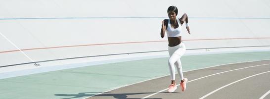 hermosa joven africana con ropa deportiva corriendo en la pista al aire libre foto