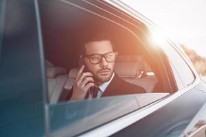 Discussing business details. Thoughtful young businessman talking on the phone while sitting in the car photo