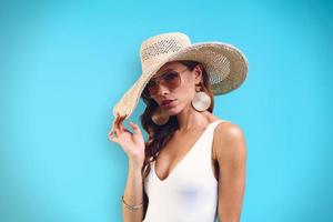 retrato de una hermosa joven con un sombrero elegante mirando a la cámara mientras se enfrenta a un fondo azul foto