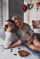 Couple in love.  Beautiful young couple drinking champagne and smiling while celebrating Valentine's Day at home photo