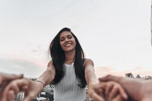 Happy to be in love. Beautiful young woman smiling and looking at camera while holding hands with her boyfriend outdoors photo