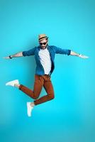 Full length of handsome young man keeping arms outstretched while hovering against blue background photo