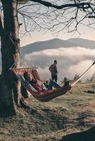 simplemente relajarse. Una joven atractiva tendida en una hamaca mientras acampaba con su novio foto