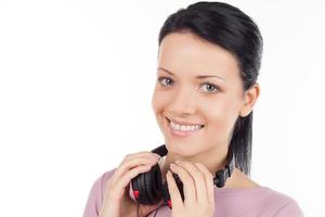 Girl with headphones. Beautiful young woman holding headphones and smiling while isolated on white photo