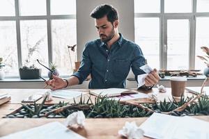 buscando inspiración. apuesto joven trabajando y arrugando papel mientras está sentado en la oficina foto