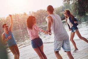 Going crazy. Full length of young people in casual wear smiling and having fun while standing on the pier photo