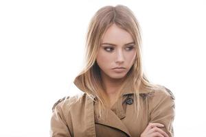 Beauty in coat. Portrait of attractive young woman in coat looking away while standing against white background photo