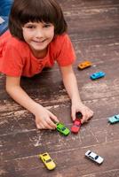 The best spending of free time. Picture of little boy lying on the floor and playing with toy cars photo