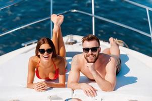 Happy to be on vacation. Cheerful young couple sunbathing while lying on the deck of yacht photo