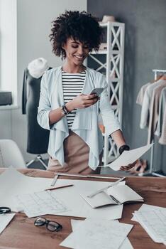 compartiendo nuevas ideas. hermosa joven africana tomando una foto de un papel usando su teléfono inteligente mientras está de pie en su taller