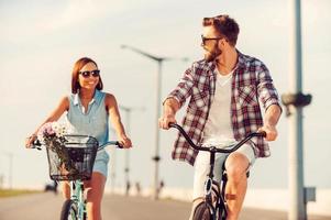 Time for fun. Happy young couple riding on bicycles and smiling photo