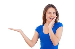 Copy space on her hand. Attractive young smiling woman holding a copy space and smiling while standing isolated on white photo