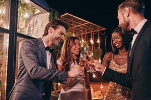 Group of people in formalwear toasting with champagne and smiling while spending time on luxury party photo