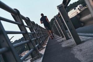 Faster than ever. Full length rear view of young African man in sports clothing jogging while exercising outdoors photo