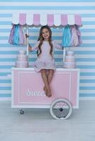 Princess on candy cart.  Cute little girl looking at camera and smiling while sitting on the candy cart decoration photo