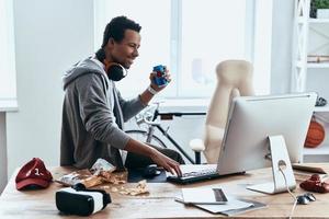 Taking a break. Relaxed young man in casual clothing smiling and typing something while spending time at home photo