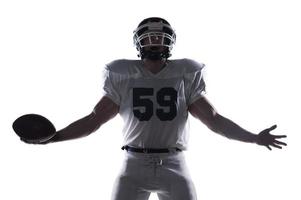 Giving himself to the game.  American football player screaming and keeping arms outstretched while standing against white background photo