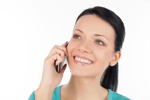 mujer en el teléfono. joven alegre hablando por teléfono móvil y sonriendo mientras está aislada en blanco foto