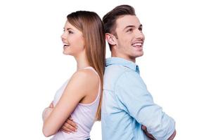 Happy couple. Beautiful young loving couple smiling and standing back to back against white background photo
