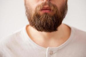 hombre con barba. imagen recortada de primer plano de la cara de un hombre barbudo aislada en gris foto