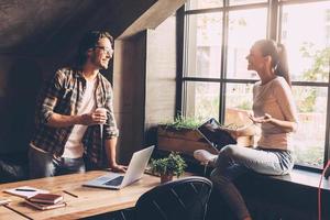 Discussing successful project. Cheerful young man and woman discussing something while having coffee break in creative office photo