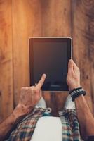 Technologies make life easier. Top view of man using digital tablet while standing on the wooden floor photo