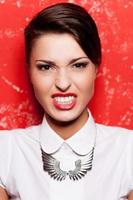 Really bad girl. Beautiful young short hair woman in white shirt posing against red background photo