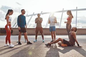 Full length of young people in sports clothing relaxing while exercising outdoors photo