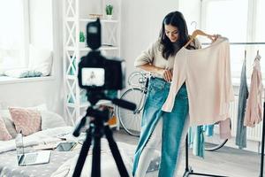 Beautiful young woman in casual clothing making social media video while spending time at home photo