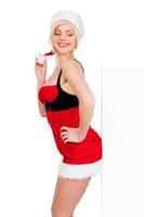 Leaning at copy space. Side view of beautiful young woman in Santa costume leaning at copy space and smiling while standing isolated on white photo