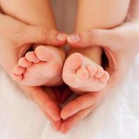 Mother care. Close-up top view of mother hands touching legs of her little baby photo