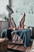 divirtiéndose atractiva mujer joven tirando una almohada y sonriendo mientras está acostado en la cama en casa foto