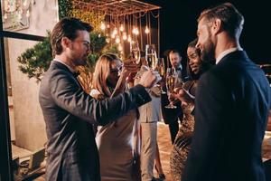 Group of people in formalwear communicating and smiling while spending time on luxury party photo