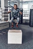 no rendirse nunca. apuesto joven africano con ropa deportiva saltando mientras hace ejercicio en el gimnasio foto