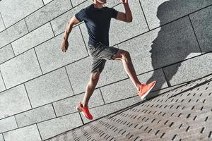 Full of energy. Close up of young man in sports clothing running while exercising outside photo