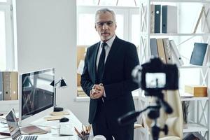 hombre mayor con elegante traje de negocios que comparte su experiencia empresarial mientras hace videos en las redes sociales foto