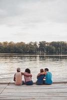 mejor lugar para descansar. hermosas parejas jóvenes abrazándose mientras se sientan en el muelle foto