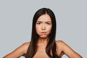 So angry Displeased young Asian woman making a face while standing against grey background photo