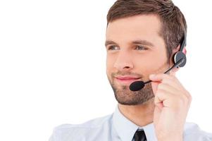 Confident customer service representative. Handsome young man in formalwear and headset looking away and smiling while standing isolated on white background photo