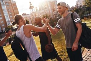amigos íntimos. grupo de hombres jóvenes en ropa deportiva gesticulando y sonriendo mientras están de pie al aire libre foto